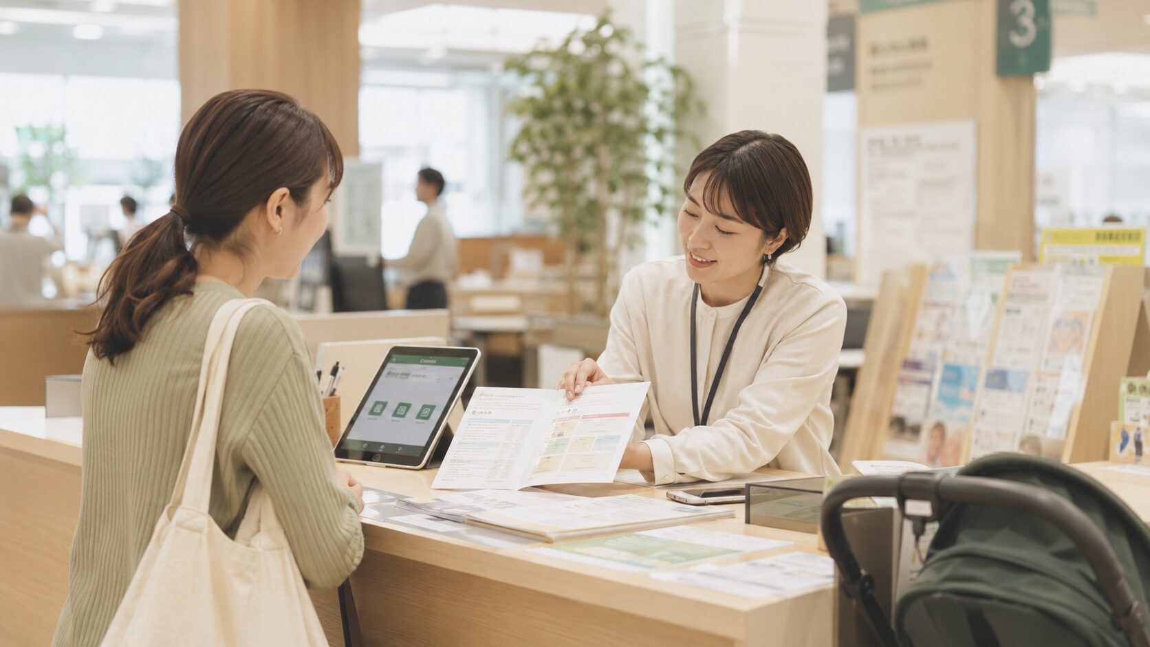 市役所窓口でタブレットを見せながら職員が商品券申請を案内